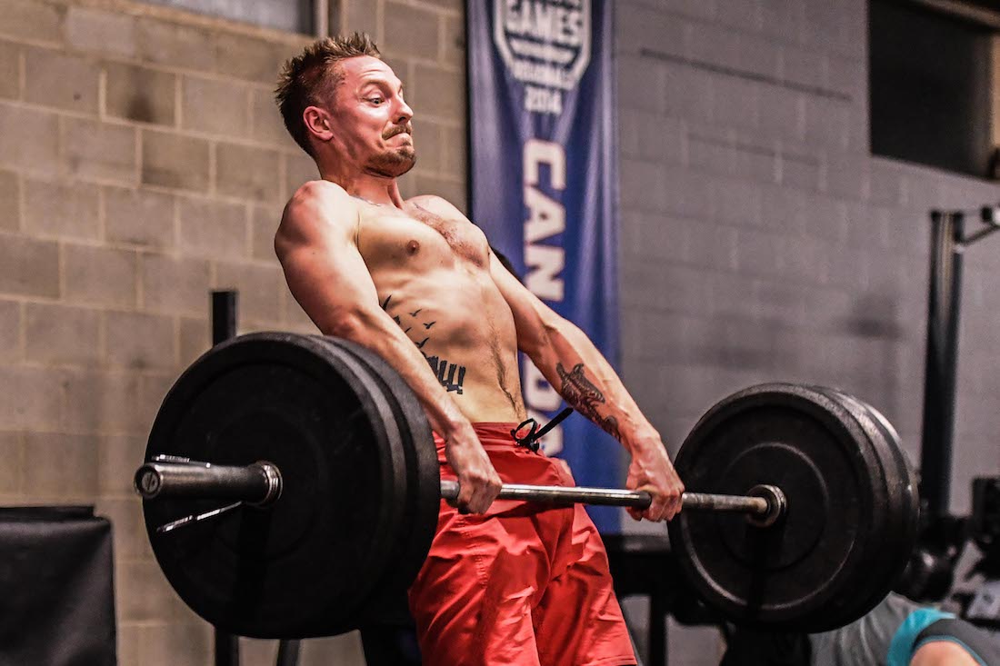 Male athlete pulls barbell in heavy clean attempt