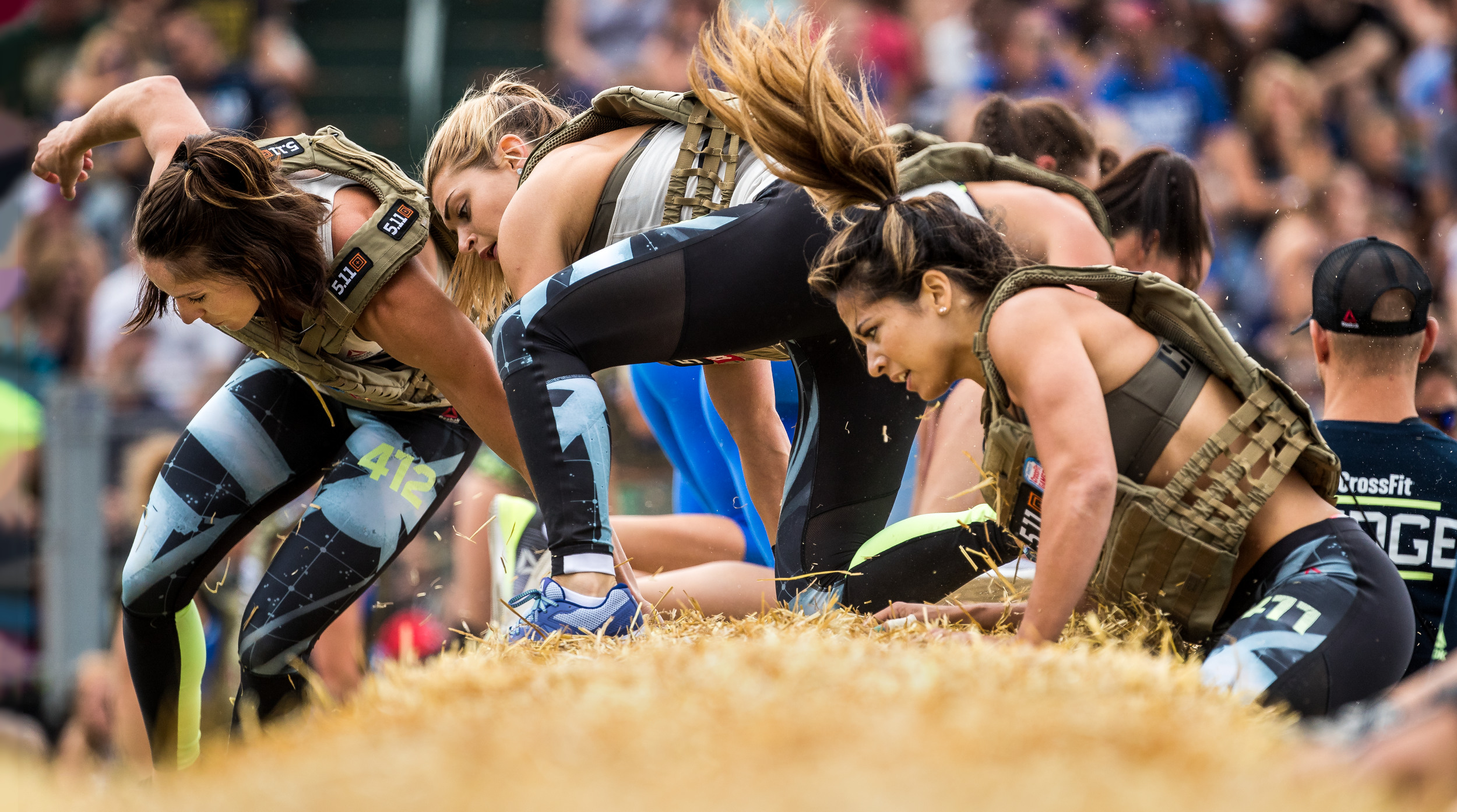 Team athletes maneuver over hay bales at the 2017 Reebok CrossFit Games 