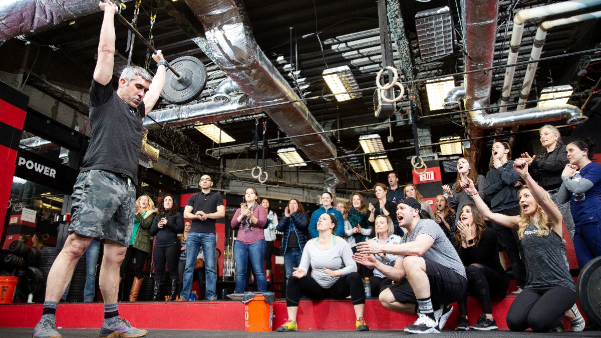 An athlete presses a barbell out overhead during the CrossFit Open